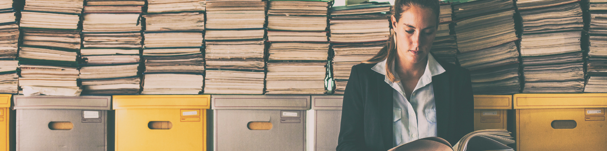 Femme représentant le syndic devant une pile d'archives en train de lire un dossier