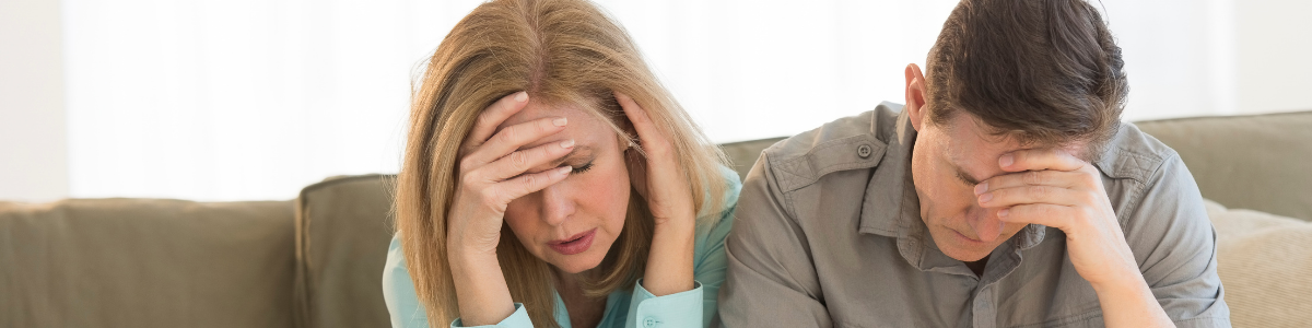 Couple désemparé ayant la main sur la tête représentant des propriétaires en impayés recevant une mise en demeure.